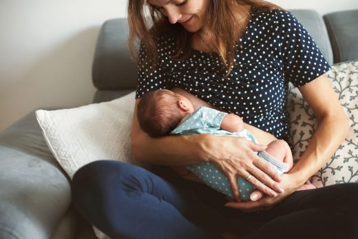 Jeune maman allaite son bébé, lui tenant dans ses bras