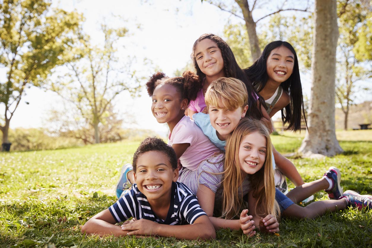 Groupe multi-ethnique d’enfants se trouvant sur l’autre dans un parc