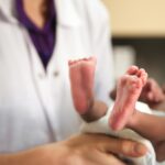 Médecin se tenant un bébé à naître, petits pieds sont visibles