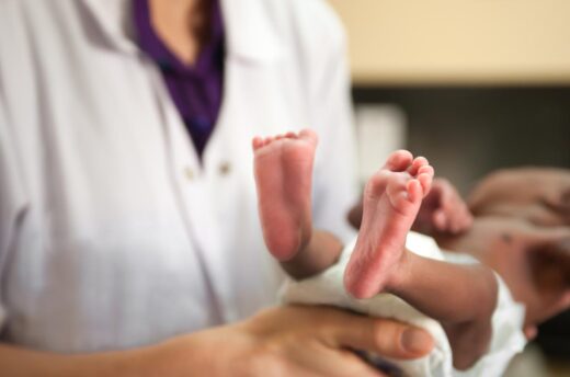 Médecin se tenant un bébé à naître, petits pieds sont visibles