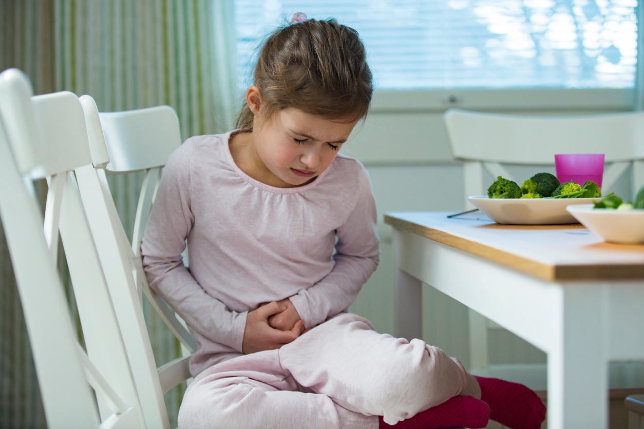 Enfant assis à la table dans la cuisine avec douleurs à l’estomac
