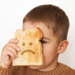 Children And Gluten. Preschool Boy With Toasted Bread, With Sad Emoji. Gluten Intolerance By Kids.